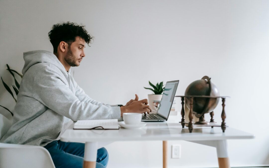 Young tech worker sitting at table working on laptop